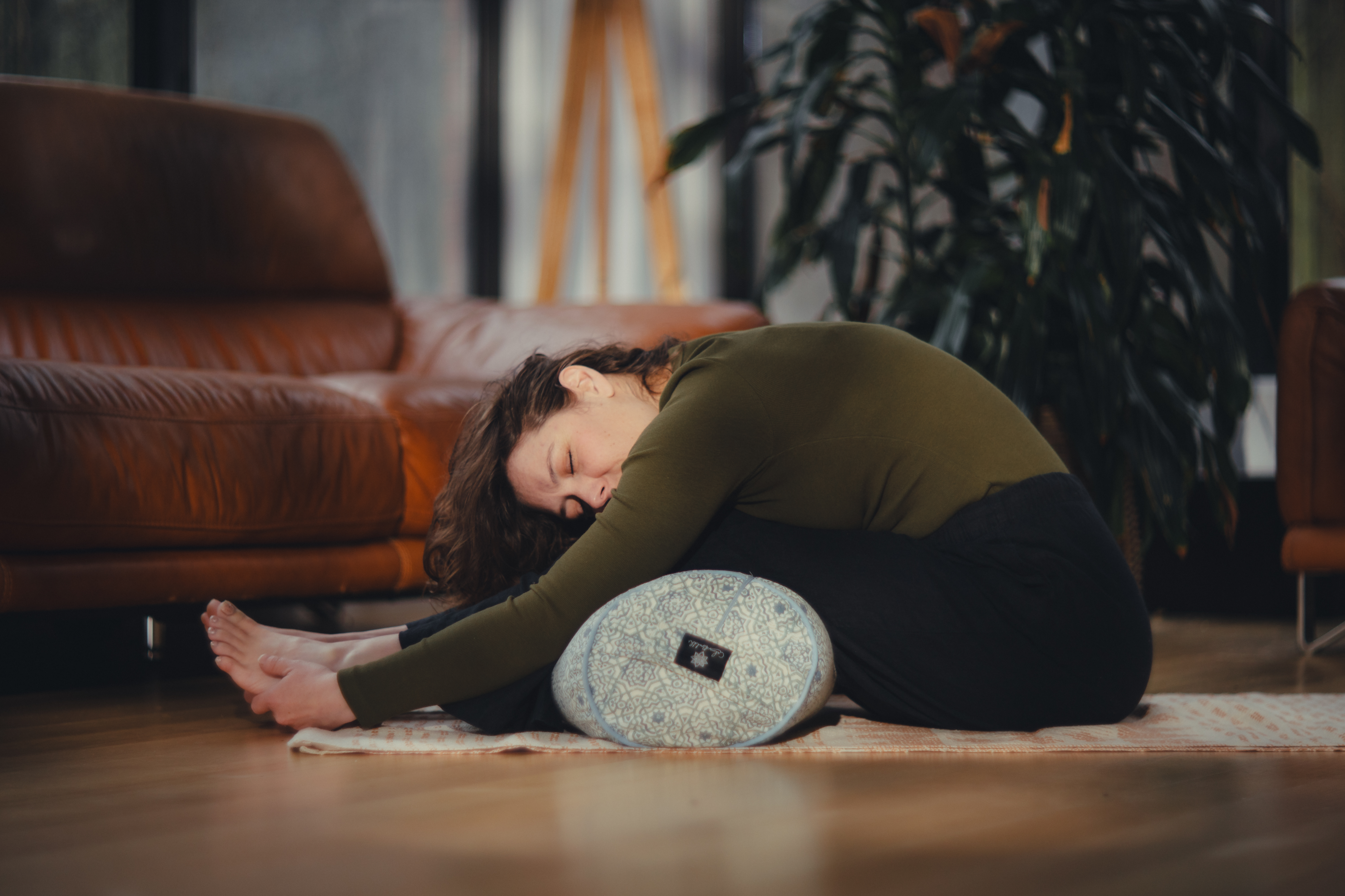 Peaceful caterpillar pose with bolster support in beautiful natural light home studio setting