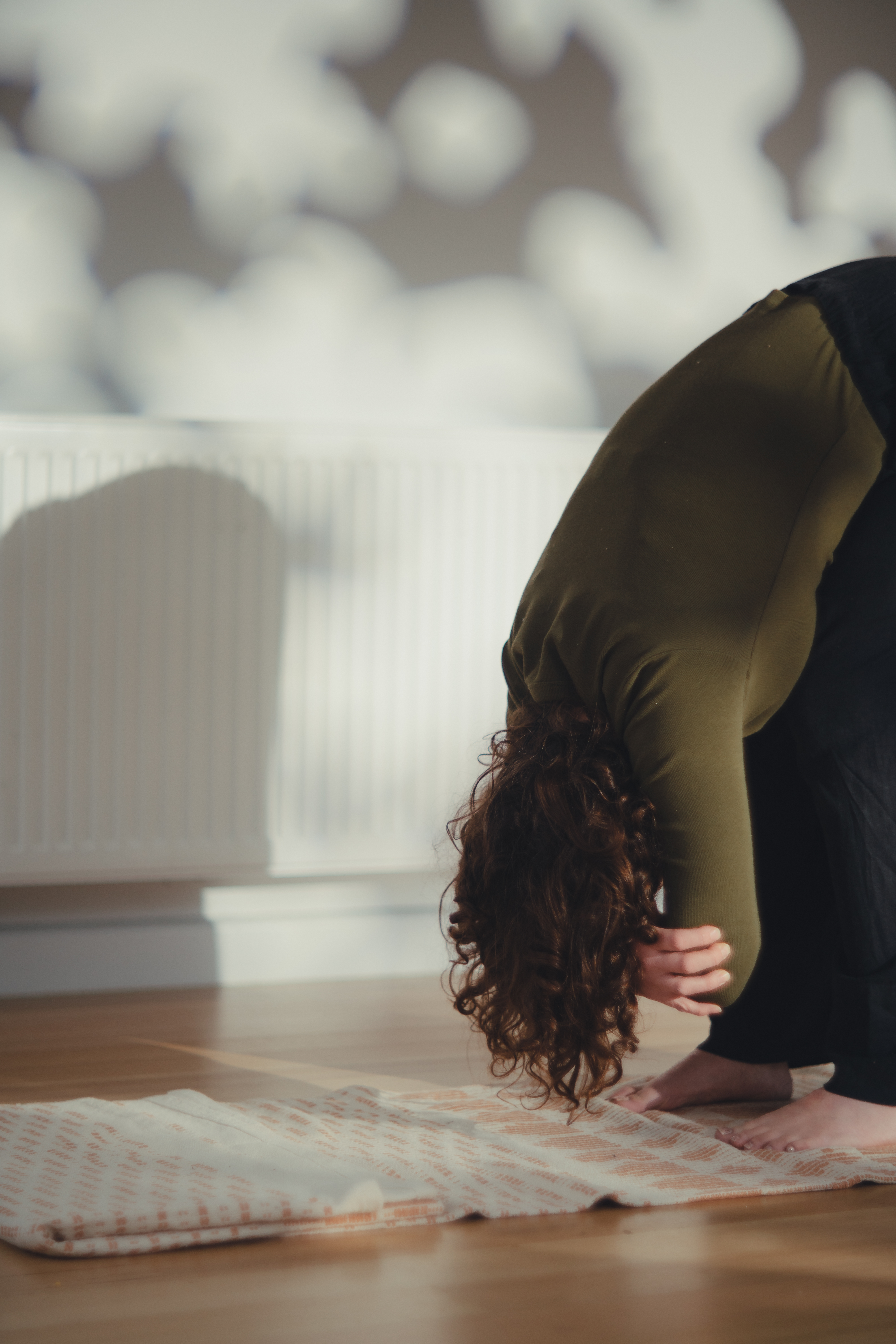 Peaceful forward fold with arms dangling in beautiful natural light home studio setting