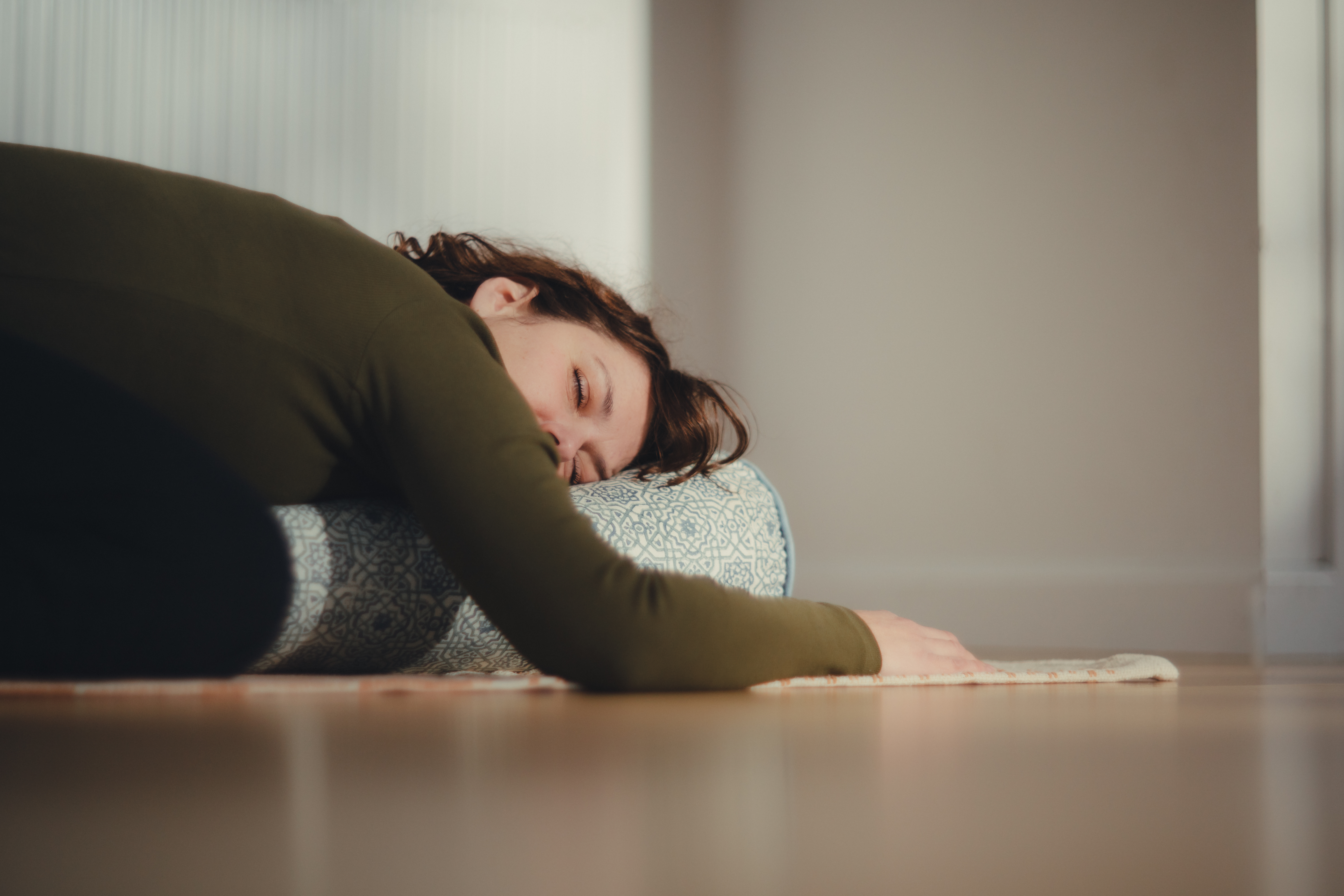 Peaceful supported rest pose with blanket in warm natural light during gentle yoga practice