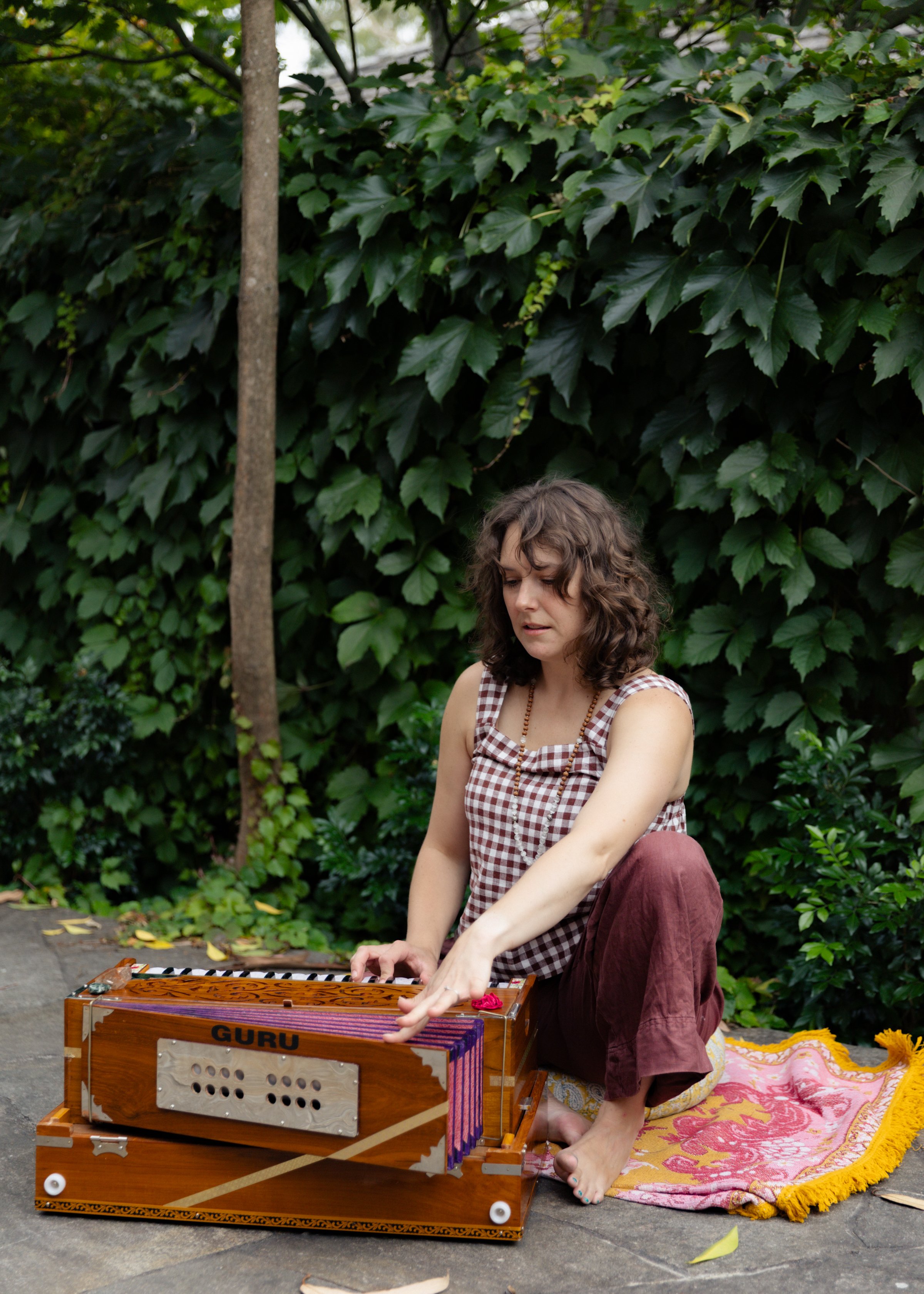 Erin playing harmonium outdoors in natural setting for meditative sound circle practice